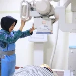 Ilustrasi seorang Ahli Teknik Radiologi mengoperasikan mesin rontgen